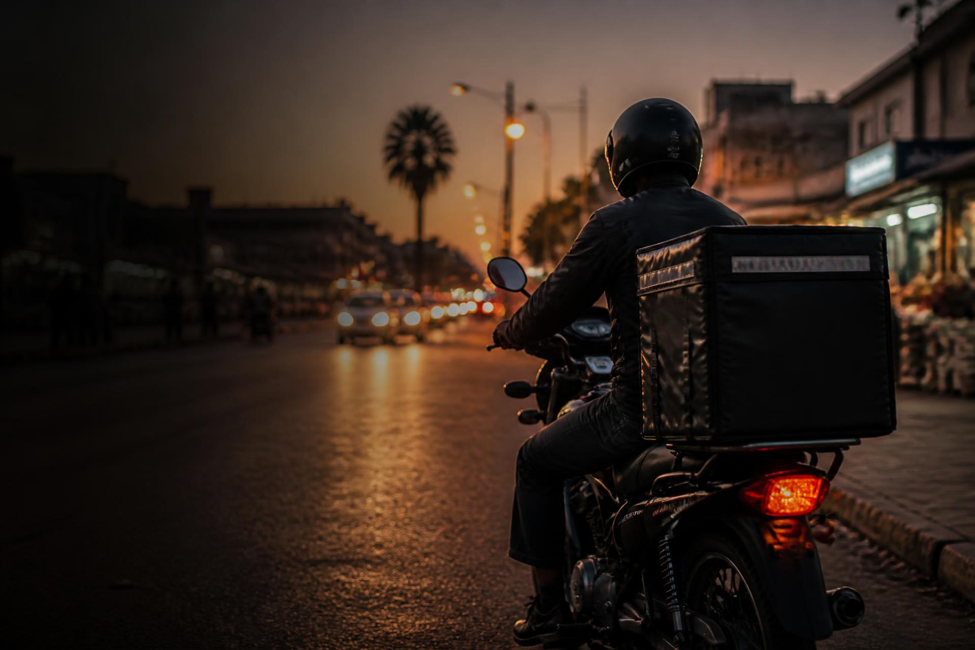 Druppa rider with a delivery box on a city street at dusk